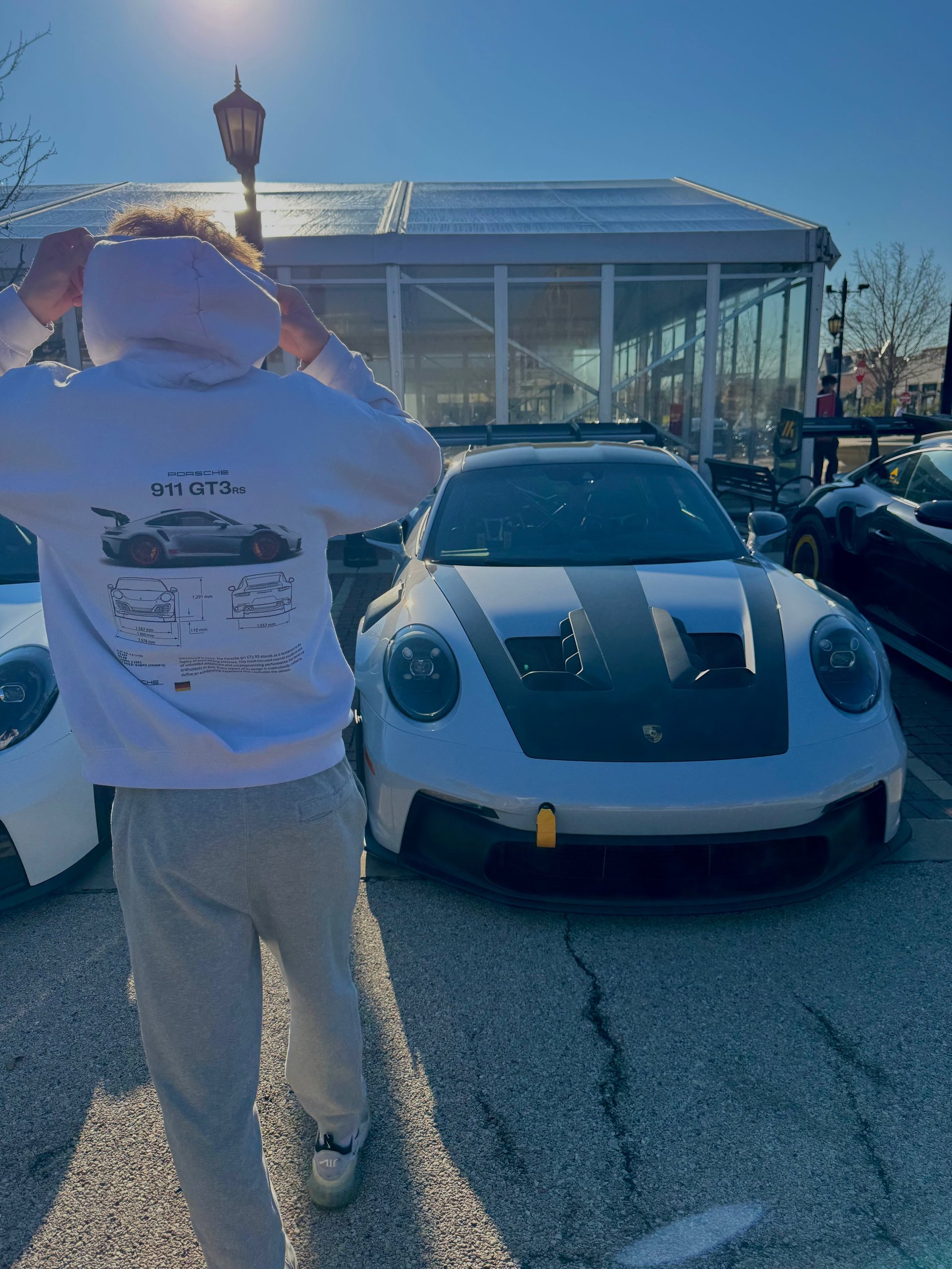 Person holding a 911 GT3 brochure standing in front of a white Porsche 911 GT3 at an outdoor car show
